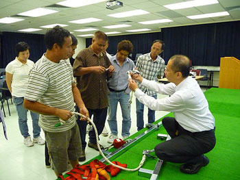 An Occupational Safety Officer taught workers at a safety seminar on how to use fall protection equipment correctly.