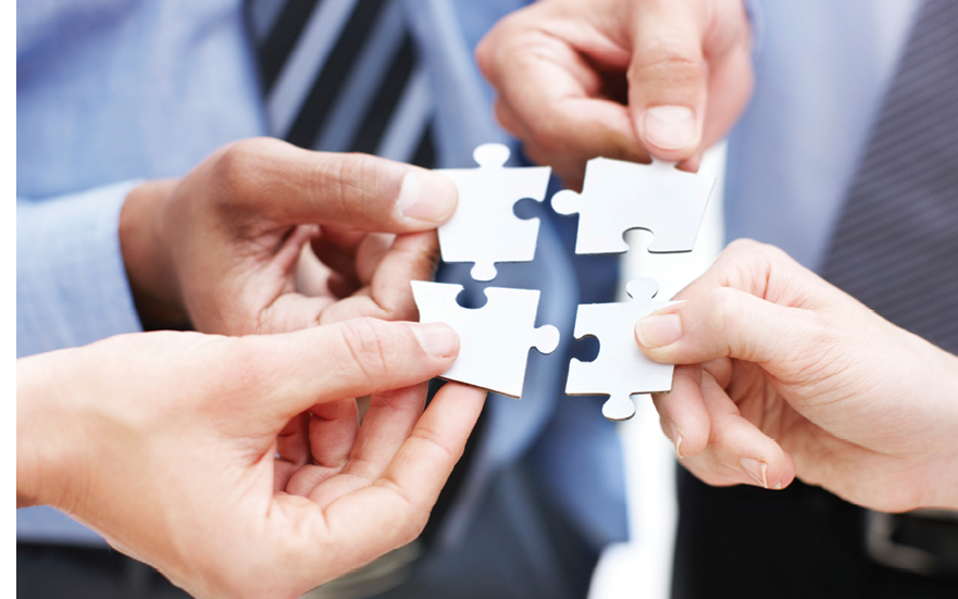 Closeup of businesspeople about to put four puzzle pieces together