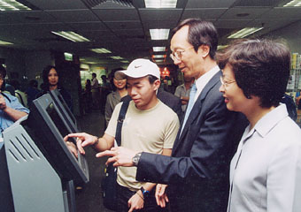 The Financial Secretary, Mr Antony Leung (second from right), trying out a touch-screen vacancy search terminal at the Job Centre.