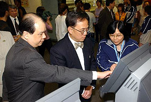 The Chief Secretary for Administration, Mr Donald Tsang, trying out the facilities at a job centre. On his right is the Permanent Secretary for Economic Development and Labour, Mr. Matthew Cheung Kin-chung.