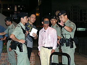 A labour inspector and policemen questioning the person-in-charge of a workplace where suspected illegal workers were detected. 